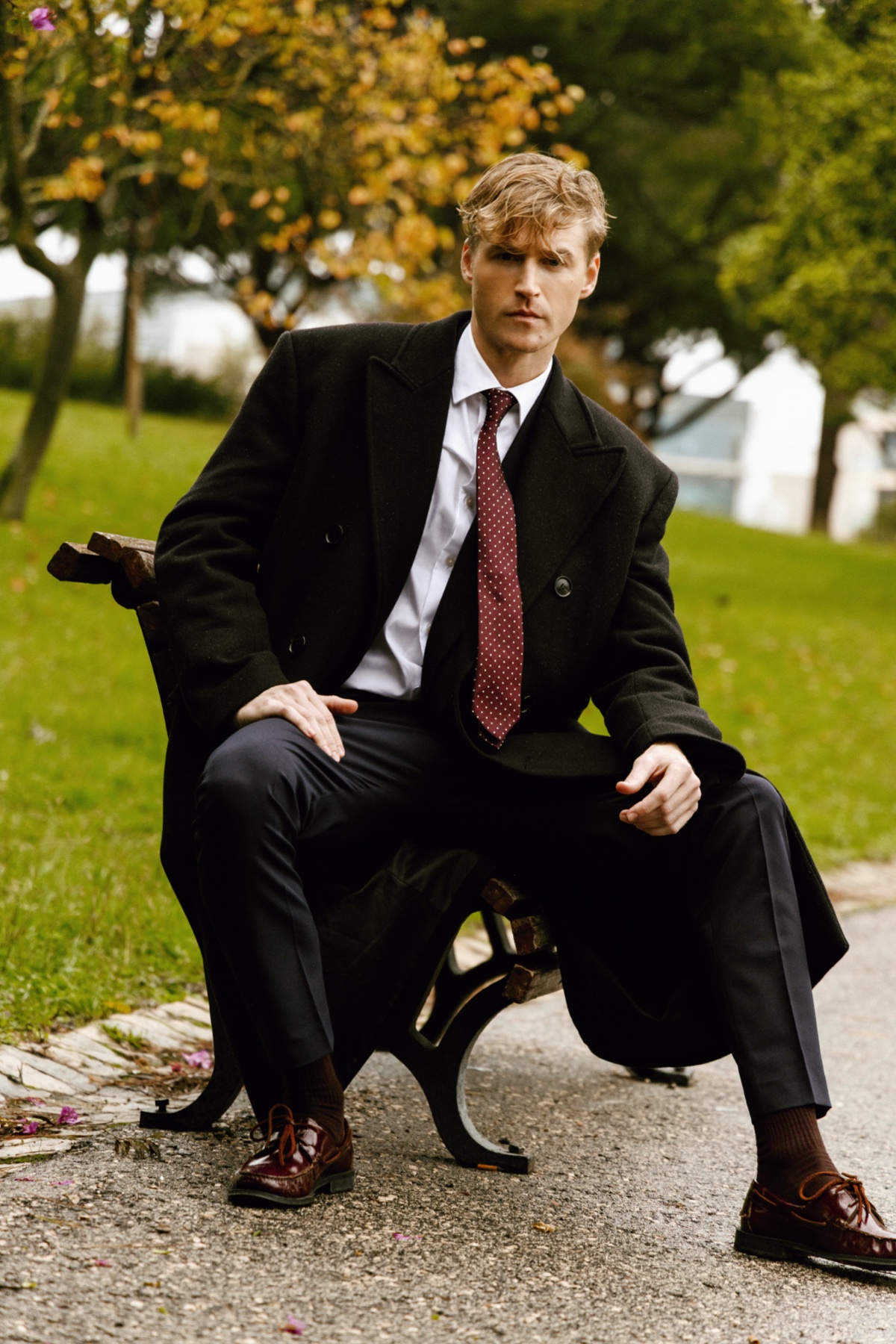 Chad J. Payne editorial — Lisbon 2025, overcoat seated on park bench, photographer David Velez