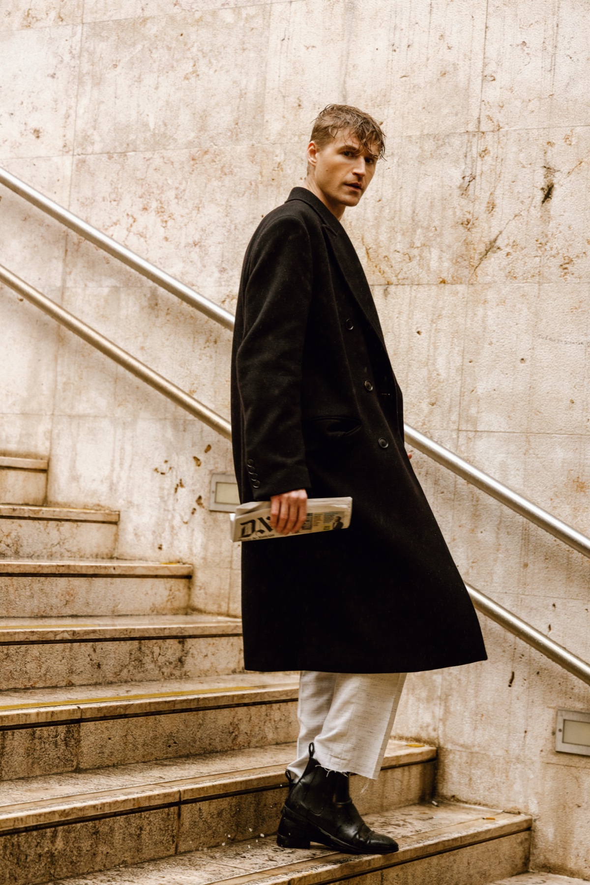 Chad J. Payne editorial — Lisbon 2025, overcoat on concrete stairs with newspaper, photographer David Velez